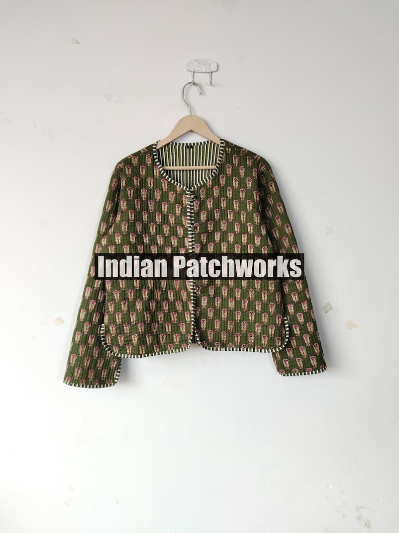 May include: A quilted jacket with a green background and a repeating pattern of red and white shapes. The jacket has a round collar and is lined with a striped fabric. The text "Indian Patchworks" is across the bottom.