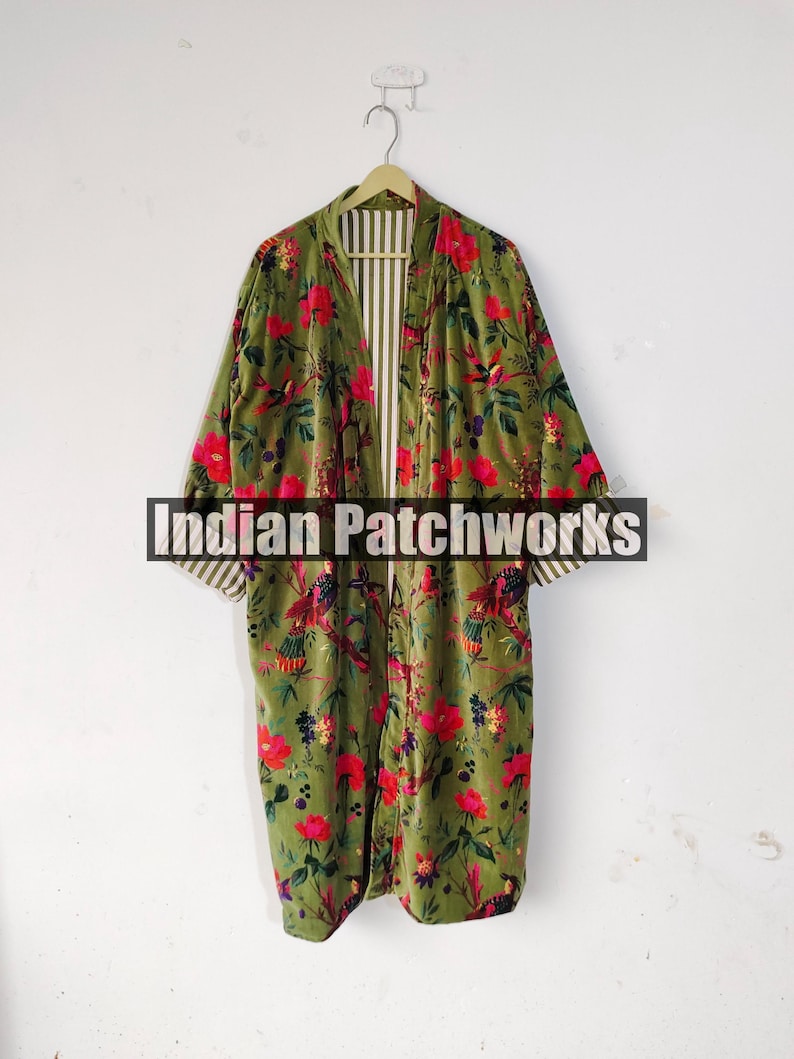 Puede incluir: Una bata larga de color verde oliva con un estampado floral de flores rojas y p&aacute;jaros. La bata tiene un interior a rayas y est&aacute; colgada de una percha de madera. El texto "Indian Patchworks" est&aacute; en la parte inferior.