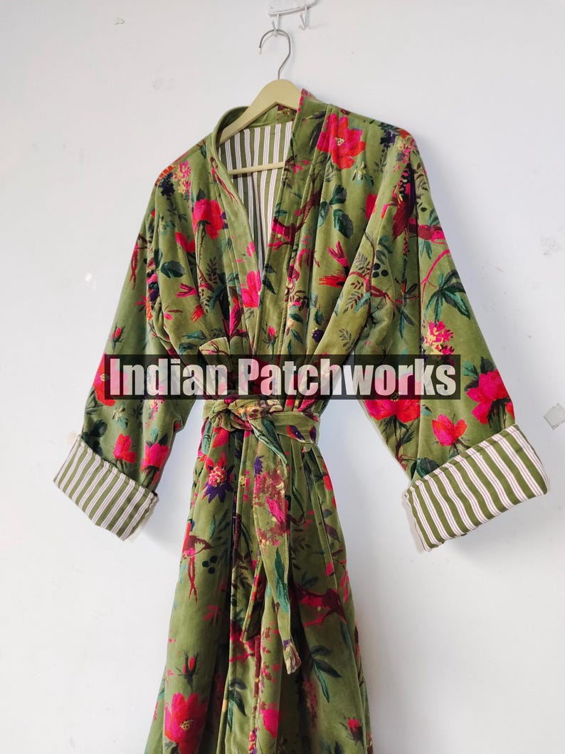 Puede incluir: Bata de terciopelo verde oliva con un estampado floral en rosa y rojo. La bata tiene forro y pu&ntilde;os a rayas. El texto "Indian Patchworks" est&aacute; en la parte delantera de la bata.