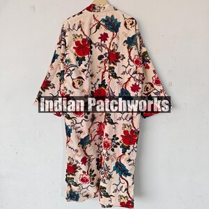 May include: A long-sleeved, cream-colored robe with a floral print featuring red, blue, and green flowers. The robe has a collar and a tie closure. The text "Indian Patchworks" is visible on the robe.