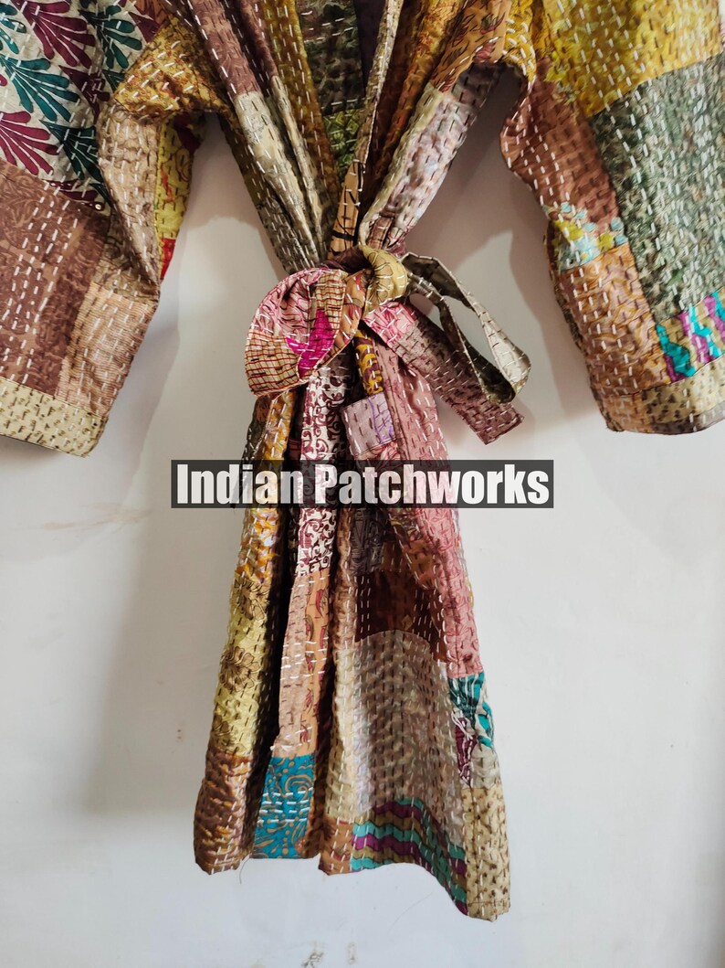 May include: A brown, beige, and pink patchwork robe with a tie belt. The robe is made of quilted fabric and has a variety of patterns. The text "Indian Patchworks" is visible on the robe.