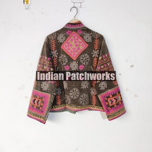 May include: A brown jacket with vibrant embroidery. The jacket displays pink, orange, and yellow floral and geometric patterns on the sleeves, back, and front. The text "Indian Patchworks" is across the front.