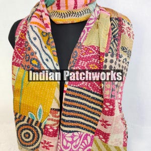 Puede incluir: Bufanda de patchwork colorida con el texto "Indian Patchworks" en la parte delantera. La bufanda presenta una variedad de patrones y colores, incluyendo amarillo, rosa y azul. La bufanda est&aacute; drapeada sobre un maniqu&iacute; negro.