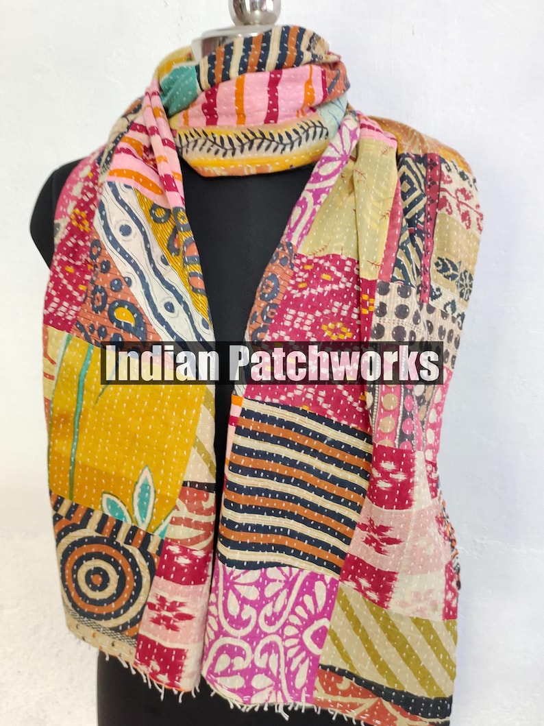 Puede incluir: Bufanda de patchwork colorida con el texto "Indian Patchworks" en la parte delantera. La bufanda presenta una variedad de patrones y colores, incluyendo amarillo, rosa y azul. La bufanda est&aacute; drapeada sobre un maniqu&iacute; negro.