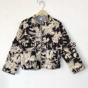 May include: A black and white floral print quilted jacket with a mandarin collar and two patch pockets. The jacket has a striped trim around the collar, pockets, and cuffs.