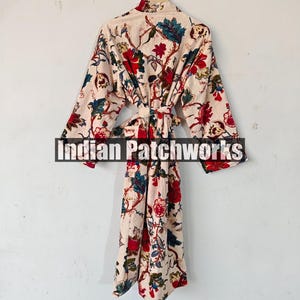 May include: A cream-colored robe with a floral print in shades of red, blue, and green. The robe has a long, flowing silhouette and a tie belt.