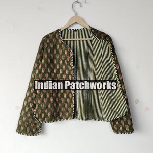 Puede incluir: Chaqueta acolchada verde oliva con un estampado floral en el exterior y un interior a rayas. La chaqueta tiene cuello redondo y cierre de botones. El texto "Indian Patchworks" es visible en la parte delantera.