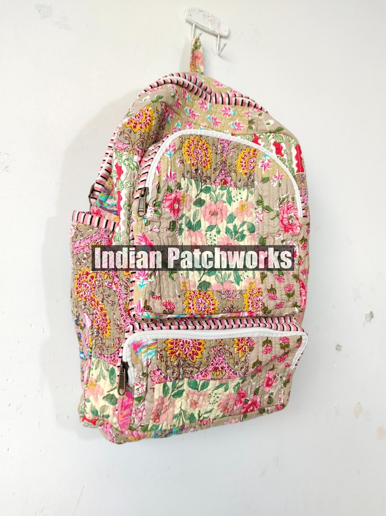 May include: A floral-patterned backpack with a beige background and pink, yellow, and green flowers. The backpack has two zippered pockets and the text "Indian Patchworks" across the front.