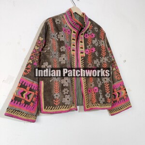 May include: A brown jacket with pink, orange, and grey floral embroidery. The jacket features a high collar and long sleeves with intricate patterns. The text "Indian Patchworks" is visible on the front.