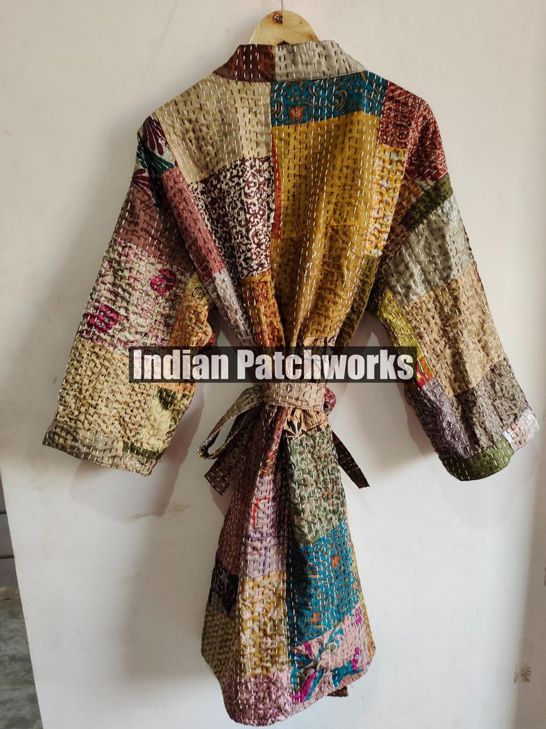 May include: A multi-colored patchwork robe with a tie belt. The robe is made of quilted fabric and has a variety of floral and geometric patterns. The text "Indian Patchworks" is printed on the robe.