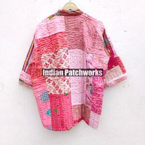 May include: A pink and white patchwork quilted shirt with a button-up front and short sleeves. The shirt has a variety of floral and geometric patterns. The text "Indian Patchworks" is printed on the shirt.