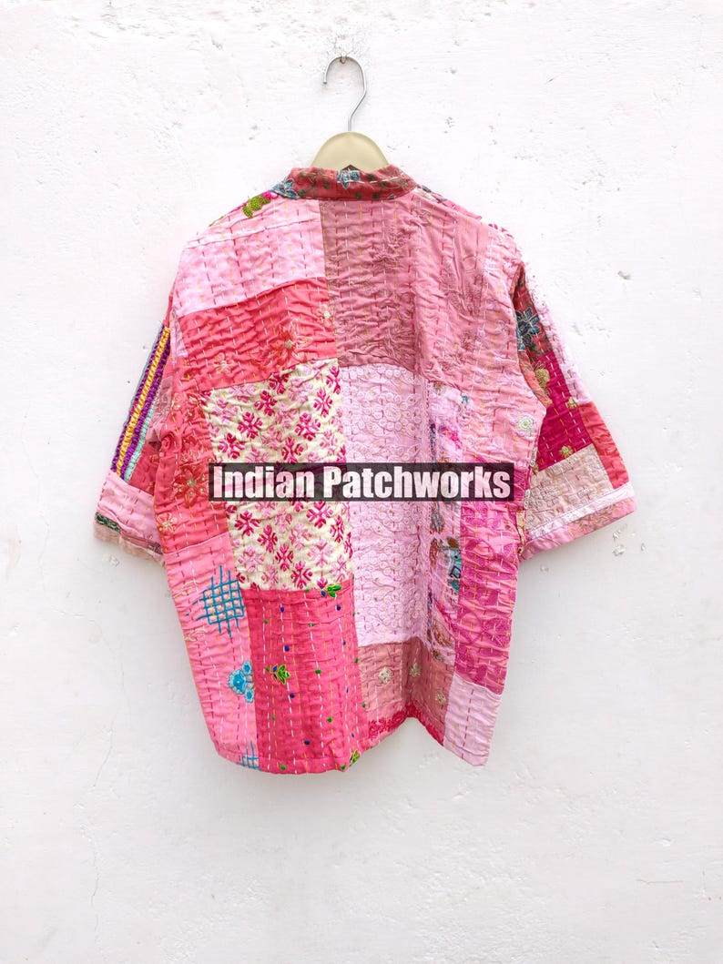 May include: A pink and white patchwork quilted shirt with a button-up front and short sleeves. The shirt has a variety of floral and geometric patterns. The text "Indian Patchworks" is printed on the shirt.