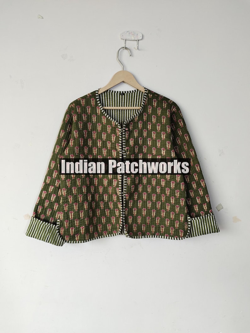 May include: Olive green quilted jacket with a repeating floral pattern in red and white. The jacket features a round collar, button closure, and striped cuffs. The text "Indian Patchworks" is across the front.