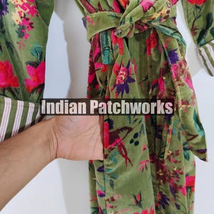 Puede incluir: Una bata verde con estampado floral y cintur&oacute;n a juego. La bata presenta un dise&ntilde;o vibrante de flores y hojas rojas, rosas y moradas. Las mangas tienen un ribete a rayas blancas y verdes. El texto "Indian Patchworks" es visible.