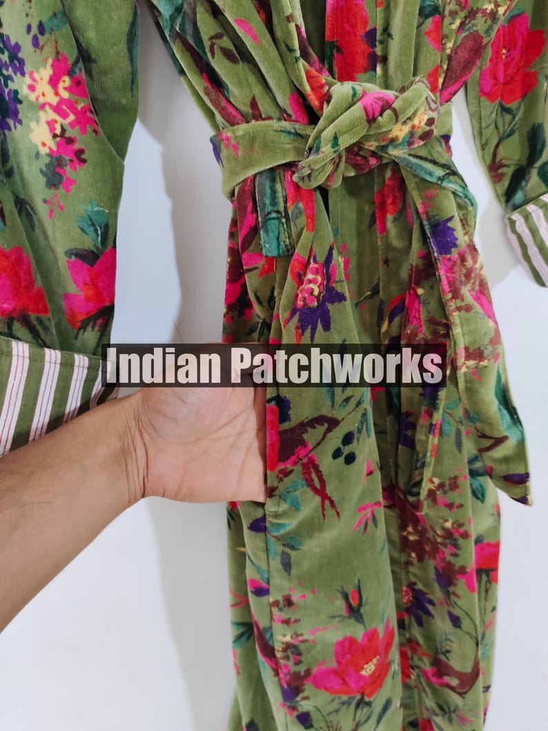 Puede incluir: Una bata verde con estampado floral y cintur&oacute;n a juego. La bata presenta un dise&ntilde;o vibrante de flores y hojas rojas, rosas y moradas. Las mangas tienen un ribete a rayas blancas y verdes. El texto "Indian Patchworks" es visible.