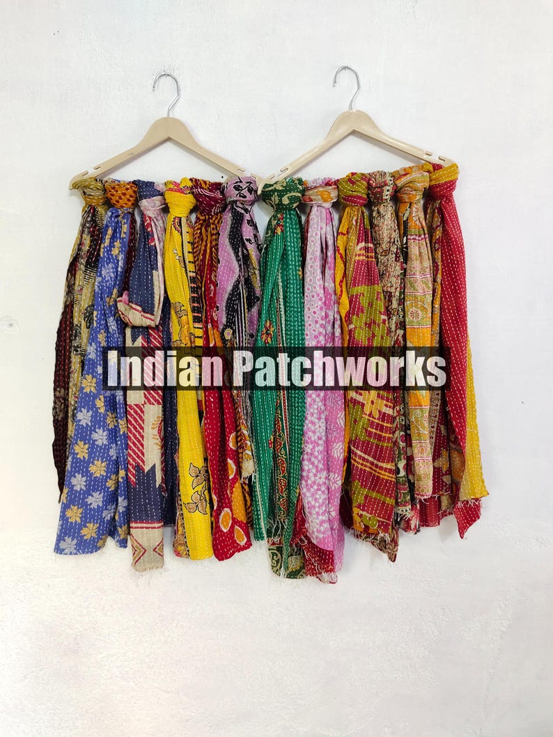 Puede incluir: Una colecci&oacute;n de coloridas bufandas estampadas colgadas de perchas de madera. Las bufandas muestran una variedad de dise&ntilde;os, incluyendo patrones florales y geom&eacute;tricos, en tonos de azul, amarillo, rojo y verde. El texto "INDIAN PATCHWORKS" es visible.