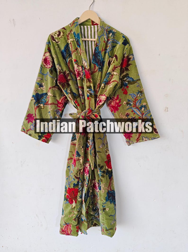 May include: A green velvet robe with a floral print and a matching tie belt. The robe has a white and green striped lining. The text "Indian Patchworks" is visible on the robe.