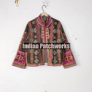 May include: A brown jacket with floral embroidery in pink, orange, and white. The jacket has long sleeves and a high collar. The text "Indian Patchworks" is visible on the bottom of the jacket.