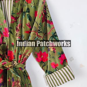 Puede incluir: Bata con estampado floral verde oliva con cintur&oacute;n anudado. La bata presenta un vibrante dise&ntilde;o floral rojo y rosa. Los pu&ntilde;os y el forro interior tienen un estampado de rayas. El texto "Indian Patchworks" es visible en la bata.