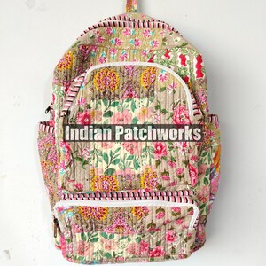 May include: Floral print backpack with white zippers and a top handle. The backpack features a beige background with pink and yellow floral patterns. The text "Indian Patchworks" is printed across the front.