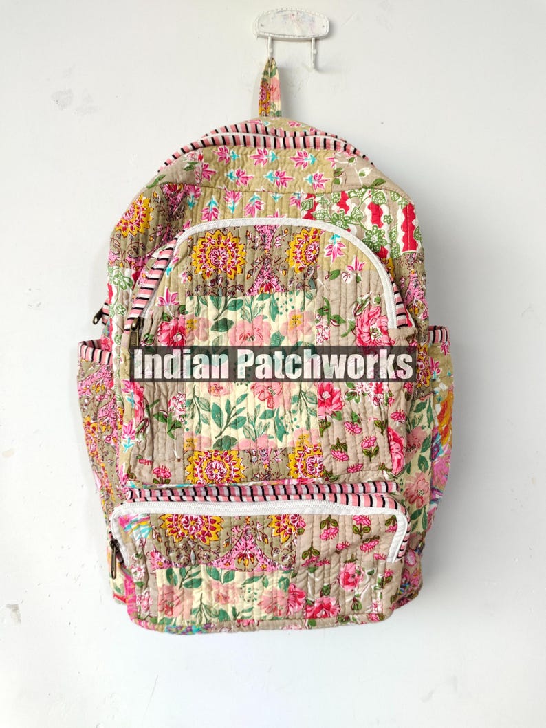 May include: Floral print backpack with white zippers and a top handle. The backpack features a beige background with pink and yellow floral patterns. The text "Indian Patchworks" is printed across the front.
