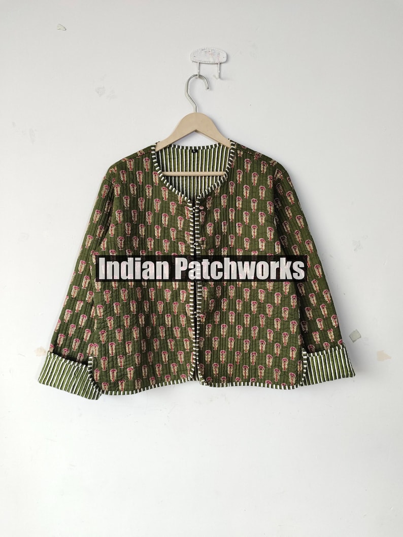 May include: Olive green quilted jacket with a repeating floral pattern in red and white. The jacket has a striped lining and trim. The text "Indian Patchworks" is across the front.