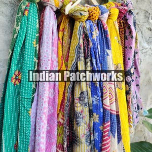 Puede incluir: Una colecci&oacute;n de coloridas bufandas estampadas colgadas de una percha de madera. Las bufandas presentan varios dise&ntilde;os, incluyendo patrones florales y geom&eacute;tricos, en tonos verdes, rosas, amarillos y azules. El texto "Indian Patchworks" es visible.