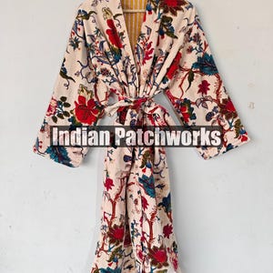 May include: A white cotton robe with a floral print in shades of red, blue, and green. The robe has a tie belt and a yellow and white striped lining. The text "Indian Patchworks" is printed on the robe.