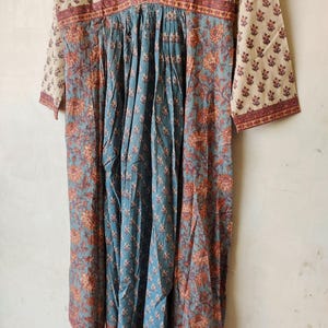 May include: A blue and white cotton dress with a floral print. The dress has a V-neckline and 3/4 sleeves. The dress is gathered at the waist and has a flowing skirt.