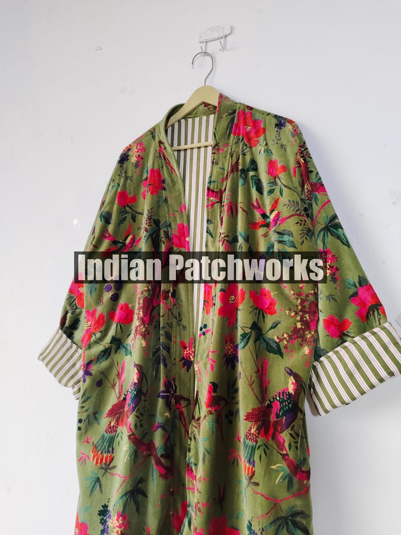 Puede incluir: Un kimono de terciopelo verde con un estampado floral y de p&aacute;jaros en rojo, rosa y amarillo. Las mangas tienen un dobladillo con tela a rayas. El texto "Indian Patchworks" est&aacute; presente.