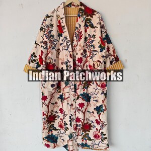 May include: A long, cream-colored robe with a floral print. The robe has a yellow and white striped lining and a button closure. The text "Indian Patchworks" is visible on the front of the robe.