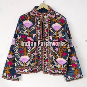 May include: A dark blue velvet jacket with intricate floral embroidery in shades of pink, purple, and orange. The jacket features a high collar and is embellished with the text "Indian Patchworks".