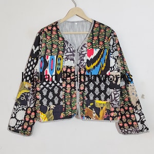 May include: A black quilted jacket with a colorful patchwork design. The jacket has a V-neck and long sleeves. The fabric is a mix of floral and geometric patterns.