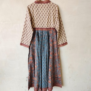 May include: A long-sleeved dress with a floral print. The top half of the dress is cream with a brown floral pattern, and the bottom half is blue with a brown and orange floral pattern.