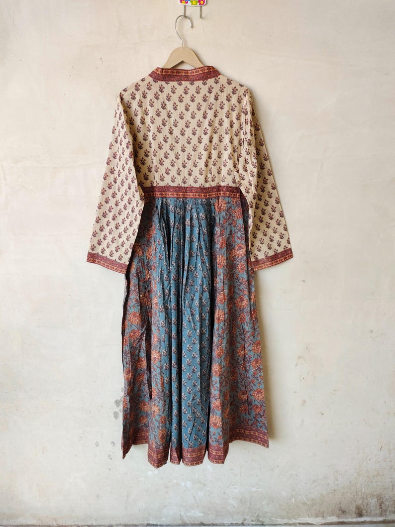 May include: A long-sleeved dress with a floral print. The top half of the dress is cream with a brown floral pattern, and the bottom half is blue with a brown and orange floral pattern.