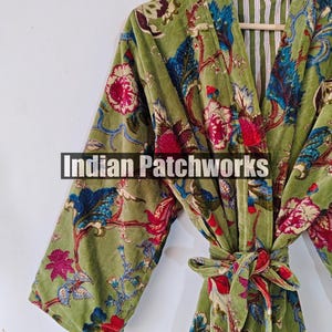 May include: A green velvet robe with a floral print and a white and green striped lining. The robe has a tie belt and long sleeves.
