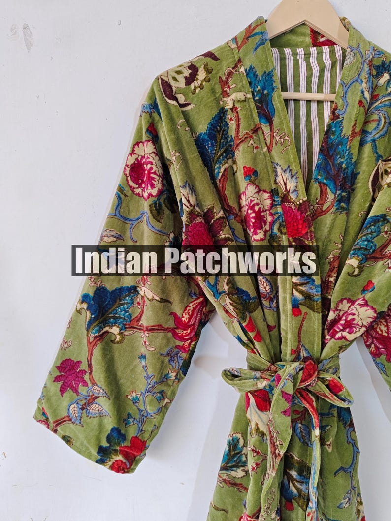 May include: A green velvet robe with a floral print and a white and green striped lining. The robe has a tie belt and long sleeves.