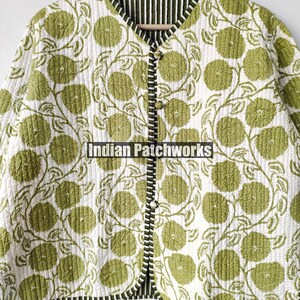 May include: A quilted jacket featuring a floral design in green on a white backdrop. The jacket has a V-neck, button closure, and black and white striped trim. The text "Indian Patchworks" is visible.