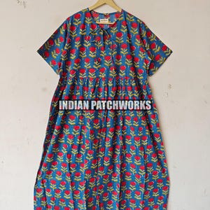 May include: Blue dress featuring a red floral print and short sleeves. The dress has a gathered waist and a button-up neckline. The text "INDIAN PATCHWORKS" is visible at the bottom of the dress.