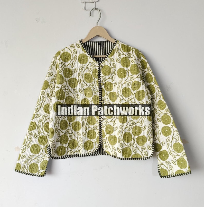 May include: A quilted jacket with a floral pattern in shades of green and white. The jacket has a black and white striped lining and black trim. The text "Indian Patchworks" is printed on the front.