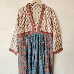 May include: A long, cream-colored dress with a V-neckline and long sleeves. The dress has a floral print in shades of brown, blue, and cream. The dress is made of a lightweight fabric and has a relaxed fit.