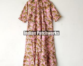 Può includere: Un vestito di cotone rosa con stampa di tigre. Il vestito ha un colletto a volant e maniche corte. Il vestito è appeso a un appendiabiti.