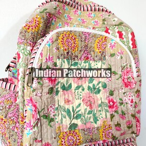May include: A quilted backpack with a floral patchwork design. The bag features a beige background with pink, yellow, and green floral patterns. The text "Indian Patchworks" is printed on the front pocket.