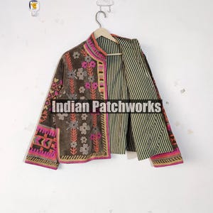 May include: A brown jacket with floral embroidery and pink and orange trim. The jacket has a striped interior and the text "Indian Patchworks" is visible on the front.