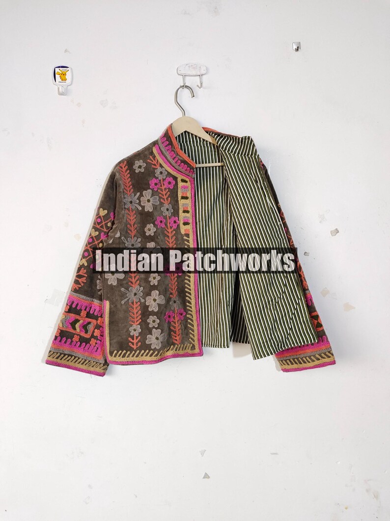 May include: A brown jacket with floral embroidery and pink and orange trim. The jacket has a striped interior and the text "Indian Patchworks" is visible on the front.