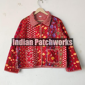 Pode incluir: Casaco acolchoado vermelho com um design de patchwork floral. O casaco tem um fecho de botões na frente, um colarinho e dois bolsos. O texto "Indian Patchworks" é visível no casaco.