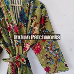 May include: A green velvet robe with a floral print and a red sash. The robe has a white and green striped lining. The text "Indian Patchworks" is visible on the robe.