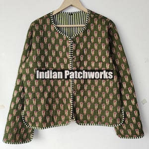 May include: Olive green quilted jacket with a floral pattern in pink and white. The jacket has a striped lining and trim. The text "Indian Patchworks" is printed on the front of the jacket.
