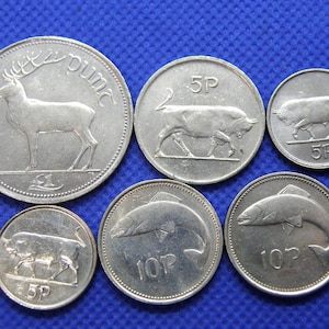 May include: A collection of six silver Irish coins featuring various animals and denominations. The coins include a 1 pound coin with a deer, a 5 pence coin with a bull, a 5 pence coin with a bull, a 5 pence coin with a bull, a 10 pence coin with a fish, and a 10 pence coin with a fish.