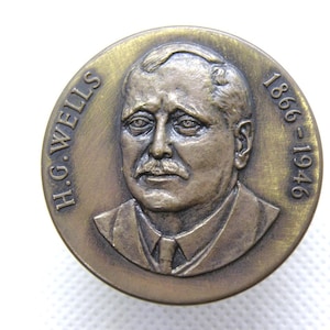 Puede incluir: Medalla de bronce con un retrato de H.G. Wells. El texto "H.G. WELLS" y los años "1866-1946" rodean la imagen. El retrato muestra a un hombre con bigote y traje.